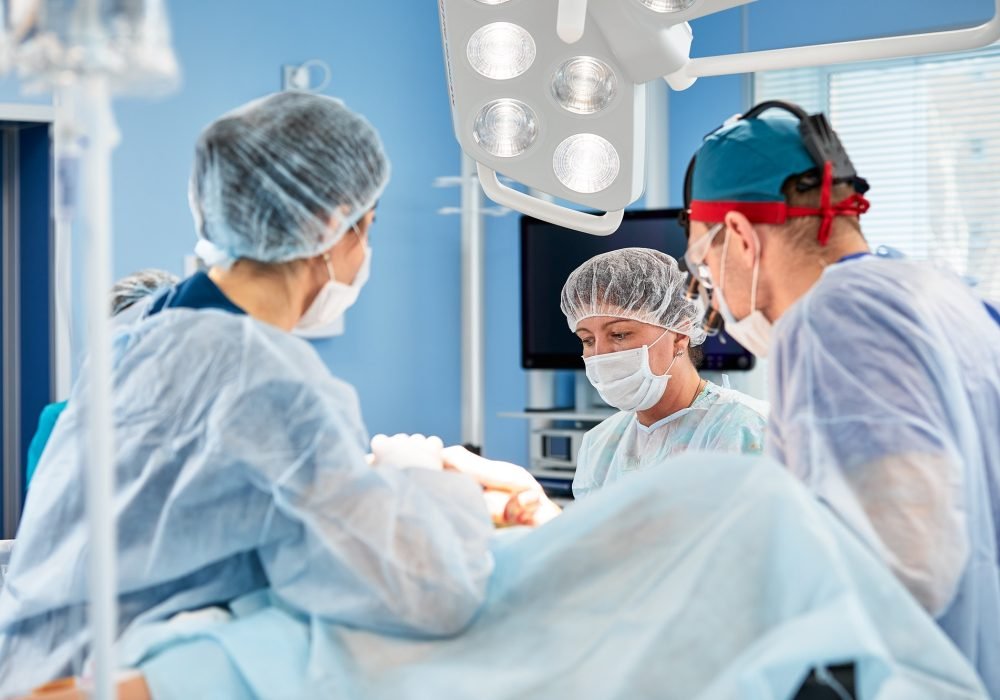 Surgeons during surgery with breast implants in their hands, installation of breast implants